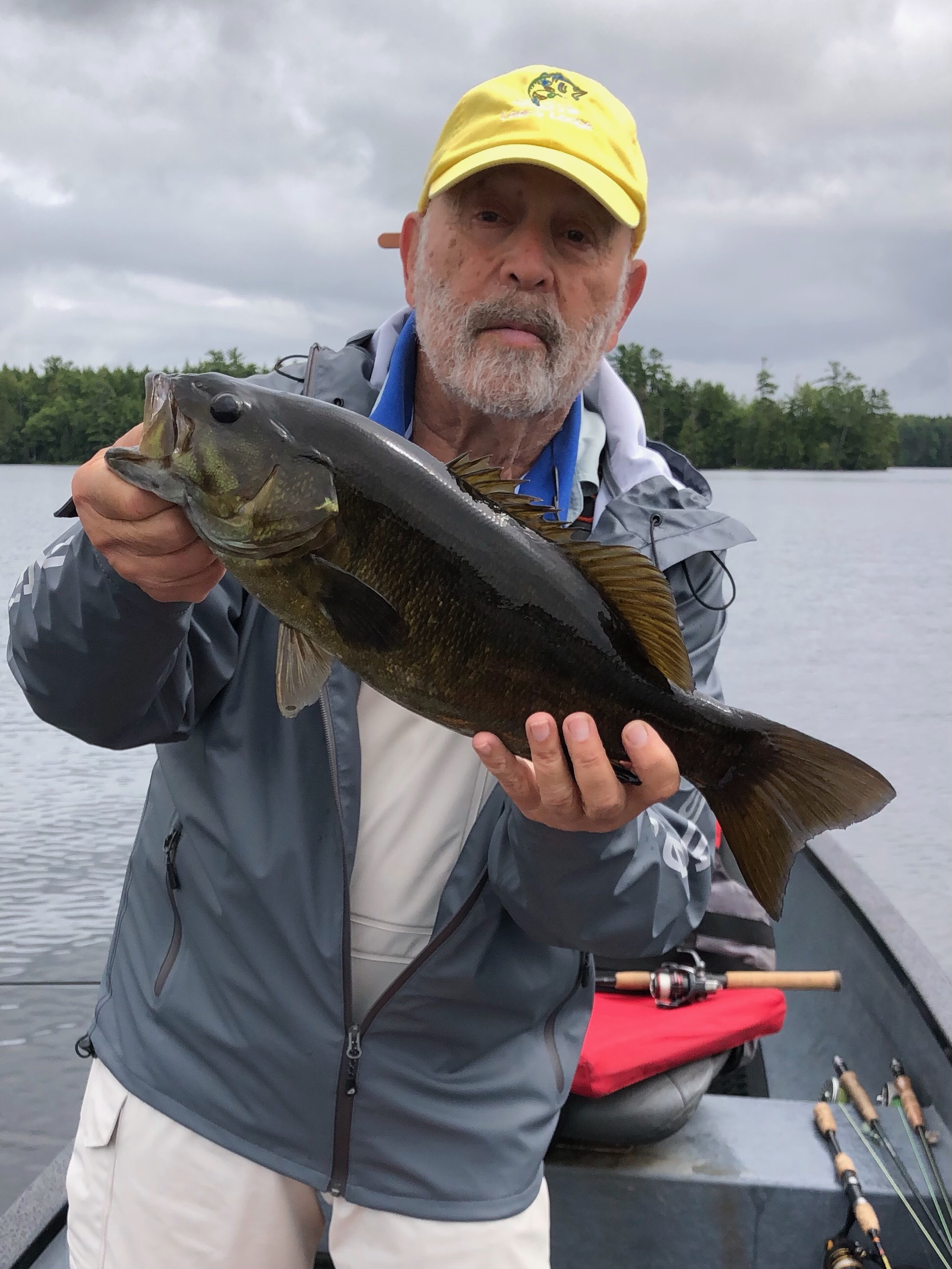 A man holding a fish while standing on top of a boat.